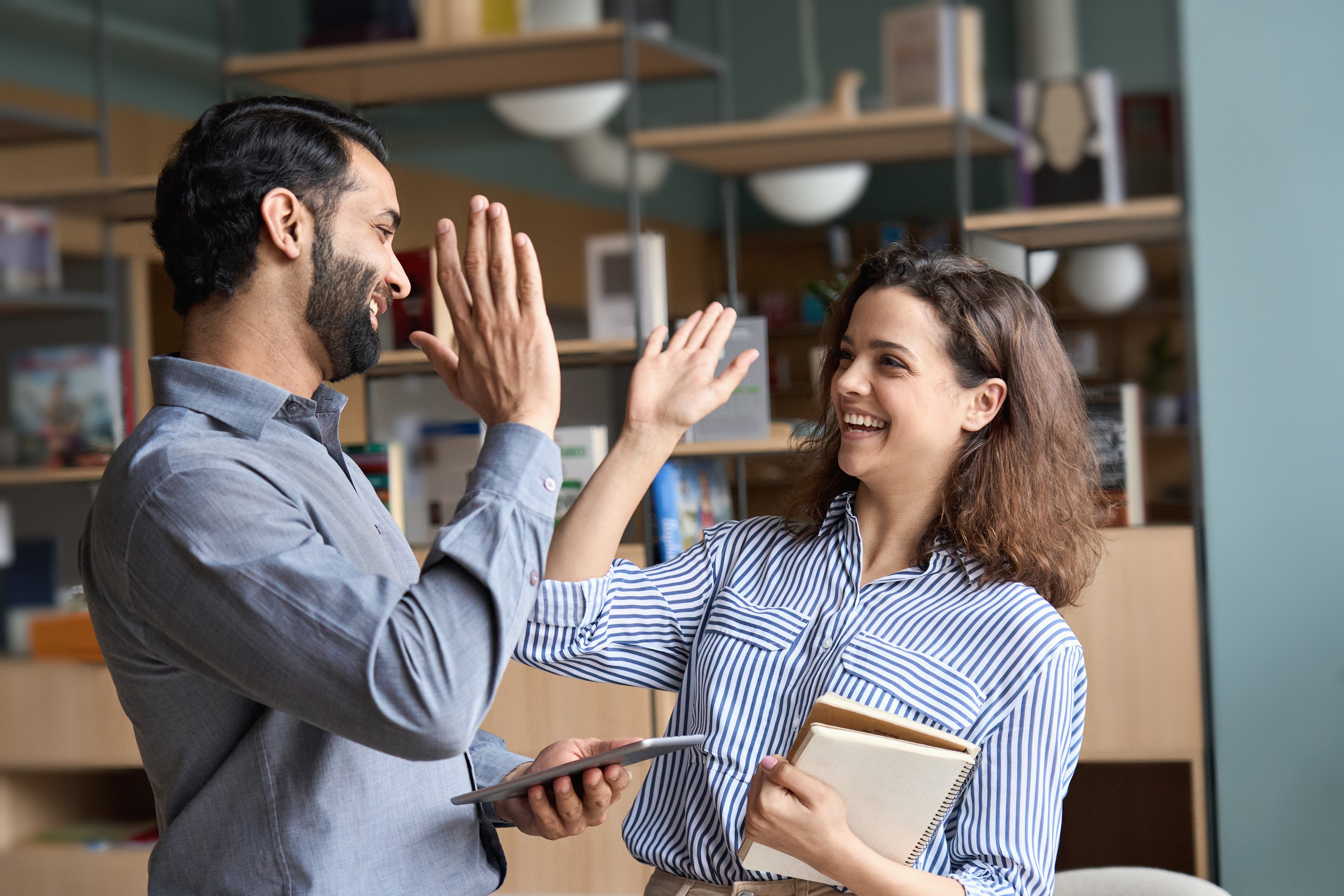 Two happy friendly diverse professionals, teacher and student giving high five standing in office celebrating success, good cooperation result, partnership teamwork and team motivation in office work.; Shutterstock ID 1937300755; purchase_order:86018; job:RH-201 - Capability statement - Singapore; client:Robert Half; other:Therese for Lyn Reviers